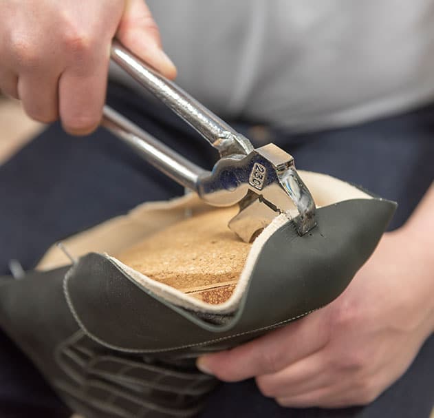 Darstellung eines Handwerkers bei der Herstellung eines Orthopädischen Maßschuhs